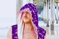 a man wearing a purple hoodie on the beach