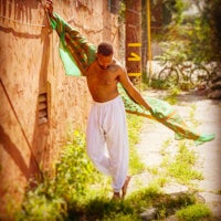 a man leaning against a wall with a green scarf