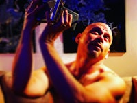 a bald man holding a camera up to his face