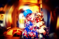 a woman wearing a blue hat holding a small dog