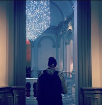a man standing in front of a chandelier in a museum