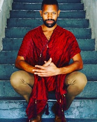 a man in a red shawl sitting on steps